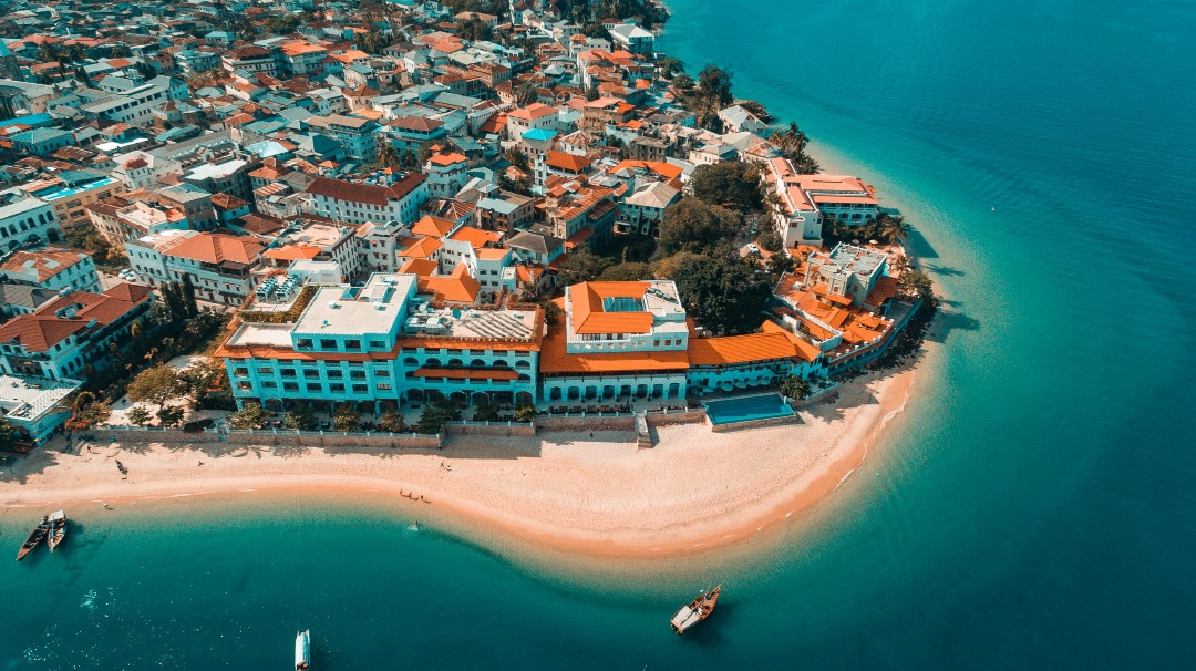 Breathtaking panoramic view of Zanzibar's pristine white sand beaches with turquoise waters and traditional dhow boats sailing in the distance